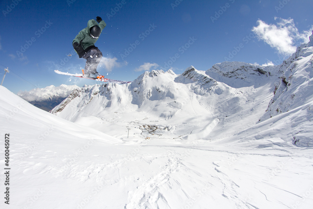 A jumping skier in the mountains. Mountain ski, winter extreme sport.