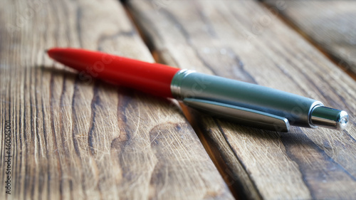 Red fountain pen on a wooden board surface. The concept of using office supplies in the village or on the farm. Diagonal. Selective focusing