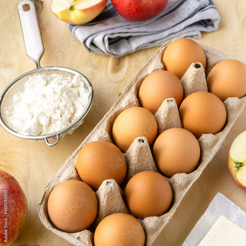 Ingredients for baking pie. Eggs, flour and apples on wooden background