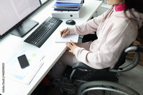 Woman in wheelchair works at computer in workplace