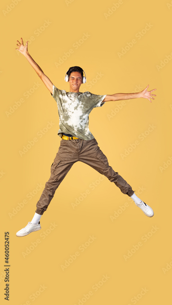 Portrait of young handsome boy, student in casual clothes jumping isolated on yellow studio backgroud. Human emotions concept.
