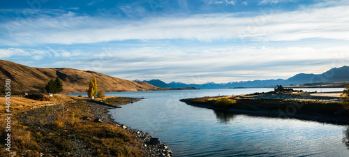 Panorama view of Lake Tekapo in autumn with Church of the Good Shepherd at right and Southern Alps in the background, Mackenzie country, South Island.
