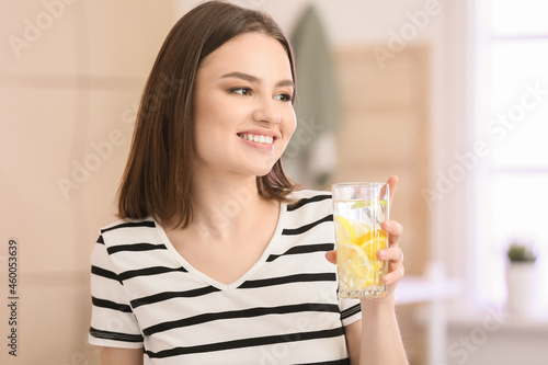 Beautiful young woman with fresh lemonade at home