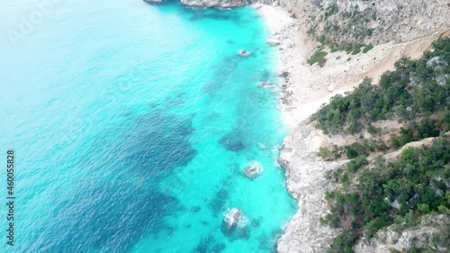 Aerial drone video of coastline and beach of Cala Goloritzé with impressive rock formation at the turquoise water of the mediterranean sea during sunset, Italy