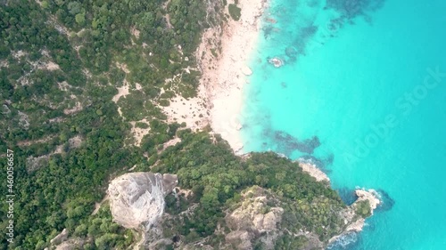 Aerial drone video of coastline and beach of Cala Goloritzé with impressive rock formation at the turquoise water of the mediterranean sea during sunset, Italy