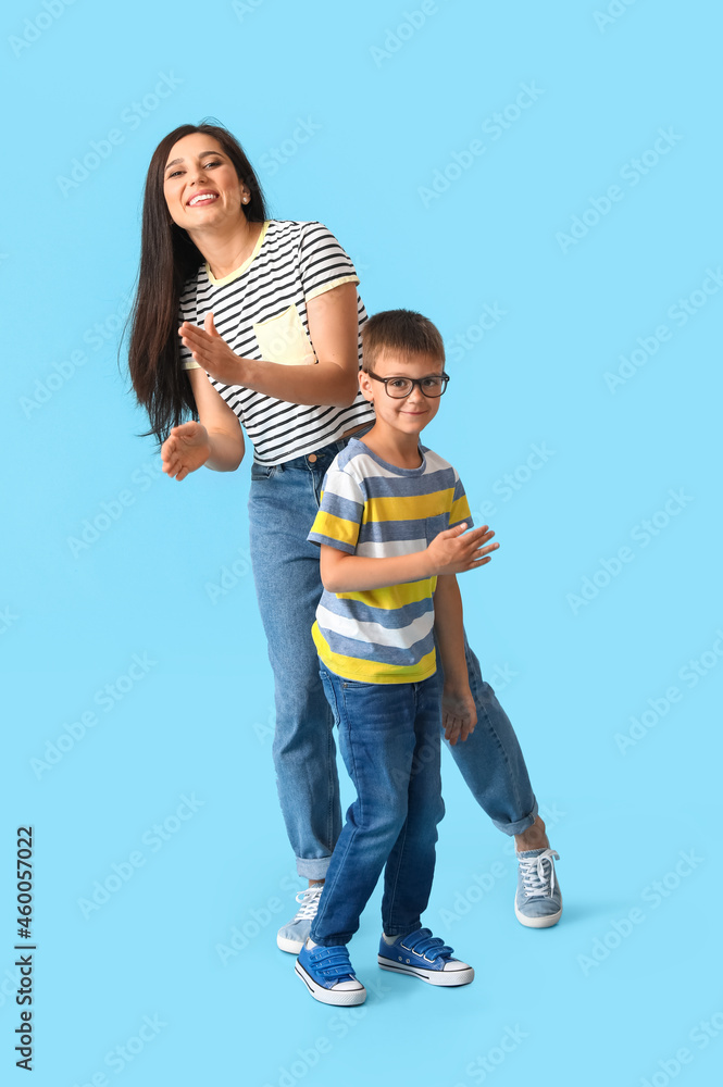Dancing young woman and her little son on color background Dancing young woman and her little son on color background