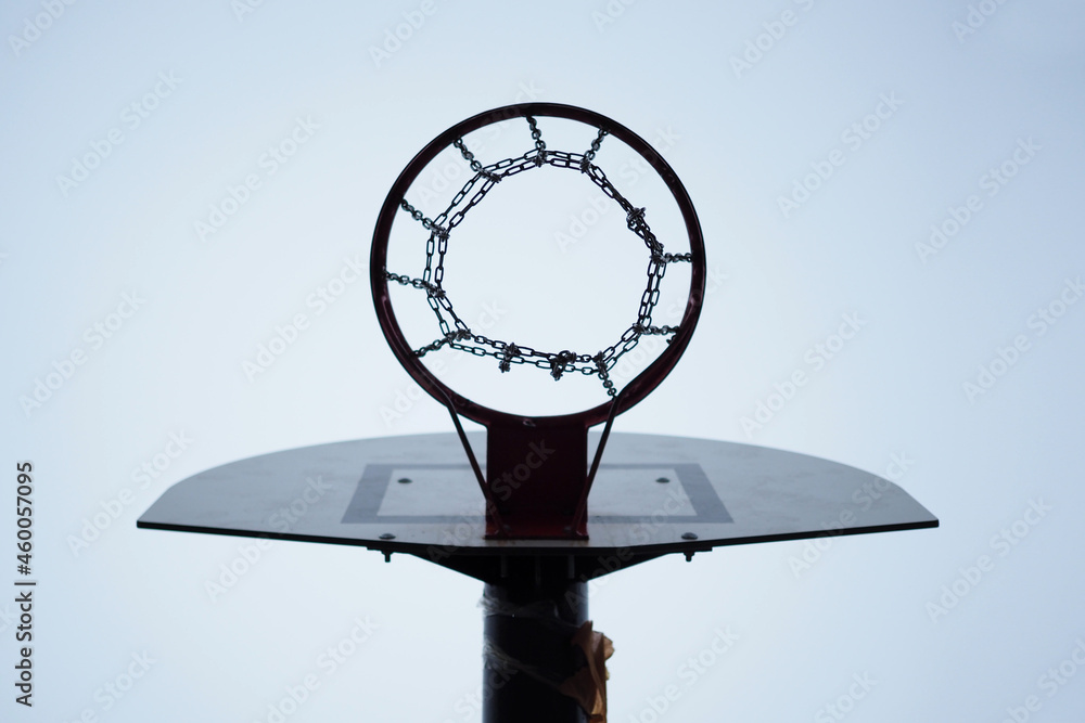Clean and cold outdoor basketball red hoop and white backboard on a cloudy day Clean and cold outdoor basketball red hoop and white backboard on a cloudy day
