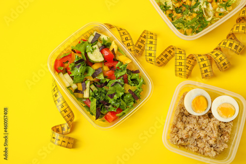 Containers with healthy food and measuring tape on yellow background, closeup