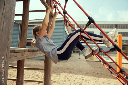 Cute little teen girl playing and climbing at playground