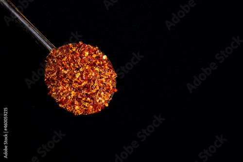 Pile crushed red pepper, Cayenne pepper, dried chili flakes isolated on black background