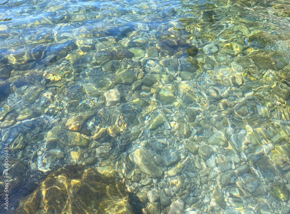Fototapeta premium Sea clear water pebbles seabed, green blue transparent rippled water. Shiny sea water. Relax, zen, meditation. Beautiful summer seascape. 