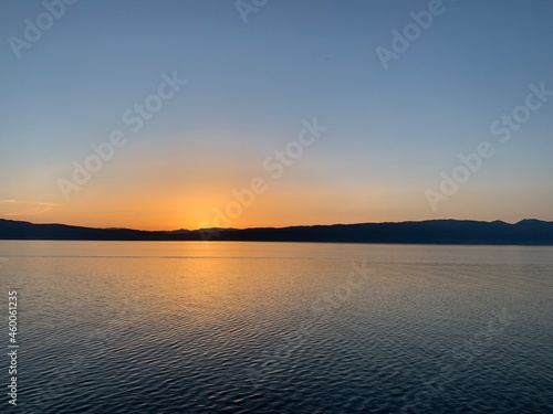 Beautiful and calm sunset on the lake with silhouette of the mountains