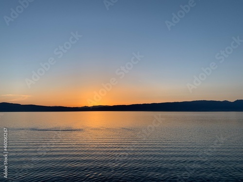 Beautiful and calm sunset on the lake with silhouette of the mountains