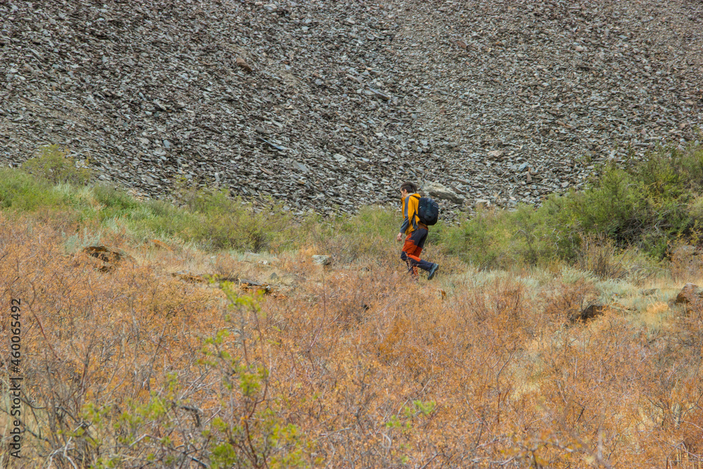 Boguty mountains, Kazakhstan - July 17 2021: A male hiker running down the grassy mountain slope Boguty mountains, Kazakhstan - July 17 2021: A male hiker running down the grassy mountain slope