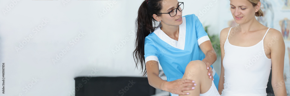 Female doctor conducts a physical examination of knee joint of patient Female doctor conducts a physical examination of knee joint of patient
