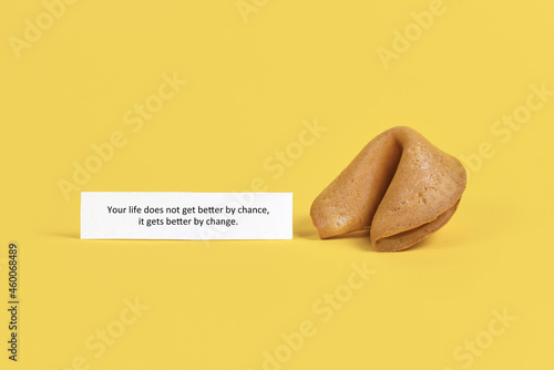 Fortune cookie note saying 'Life does not get better by chance, it gets better by change' on yellow background photo