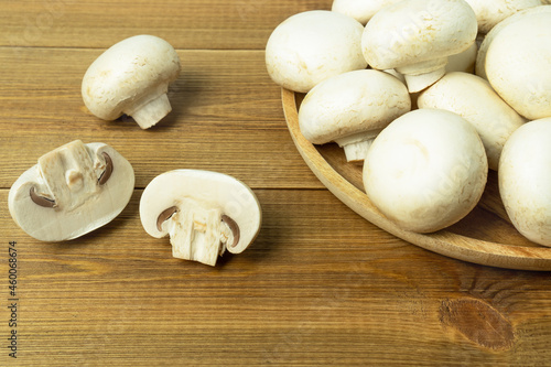Raw fresh mushrooms champignons on wooden table.