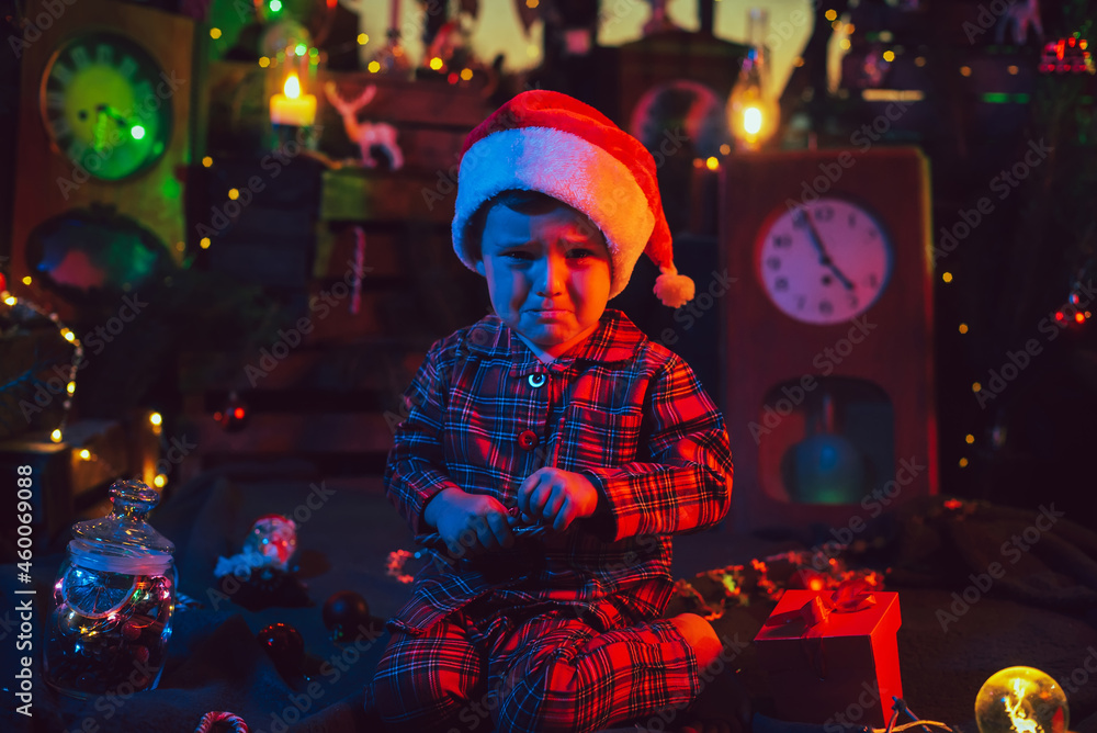 Christmas decorations. A frustrated boy is sitting on the floor.