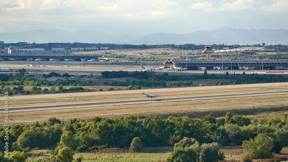 Naklejka premium Mitsubishi Crj -1000 aircraft of the Iberia Regional airline taking off from Madrid Barajas airport, also seeing the terminal and the control tower