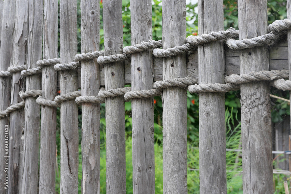 Old weathered rustic wooden fence secured with thick heavy rope Old weathered rustic wooden fence secured with thick heavy rope