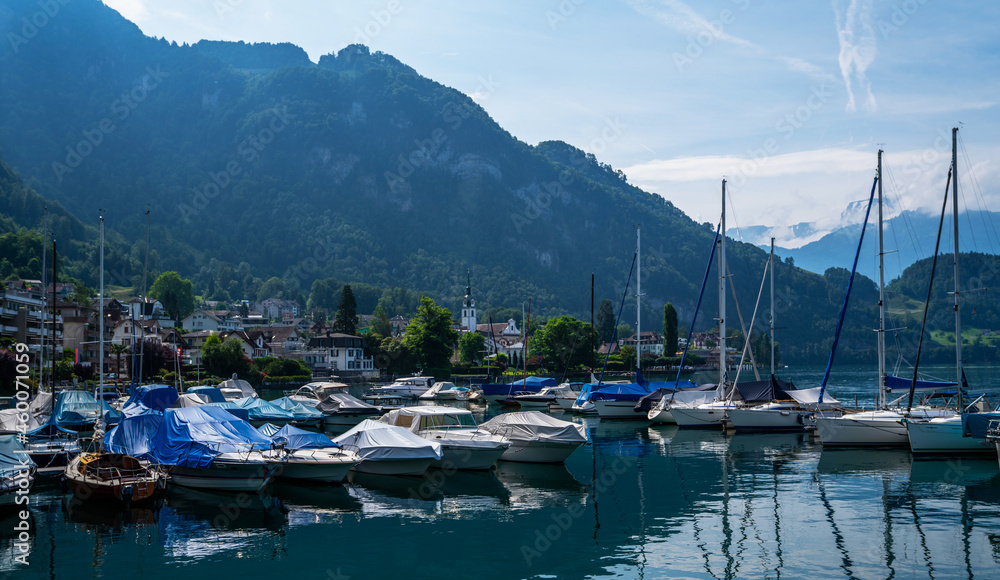 Early morning in harbor. Сoastal town Gersau of Lake Lucerne and Swiss Alps. A lot of white boats and luxury yachts moored in marina on a turquoise water, during a summer season. Travel and vacation.