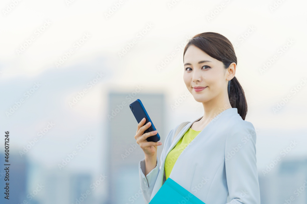 都市を背景にスマホを持つ女性 都市を背景にスマホを持つ女性