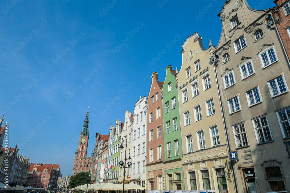 A close up of the facades of tall building in the middle of Old Town in Gdansk, Poland. The buildings have many bright colors, they are richly decorated. High tower of Town Hall. Sightseeing at night