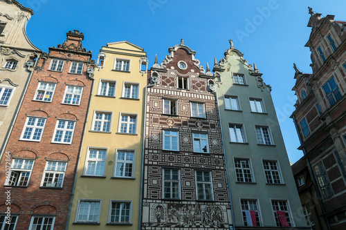 A close up of the facades of tall building in the middle of Old Town in Gdansk, Poland. The buildings have many bright colors, they are richly decorated. City tour. Clear day.