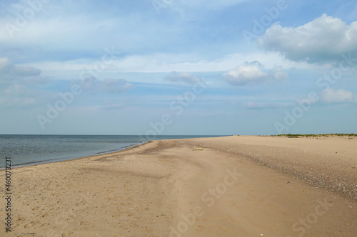 The coastal line of a sandy beach by the Baltic Sea on Sobieszewo island, Poland. The sea is gently waving. A bit of overcast. Solitude and serenity