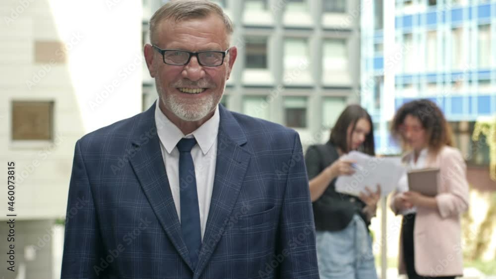 Portrait of a smiling senior businessman in the courtyard of a large business center. Portrait of a smiling senior businessman in the courtyard of a large business center.