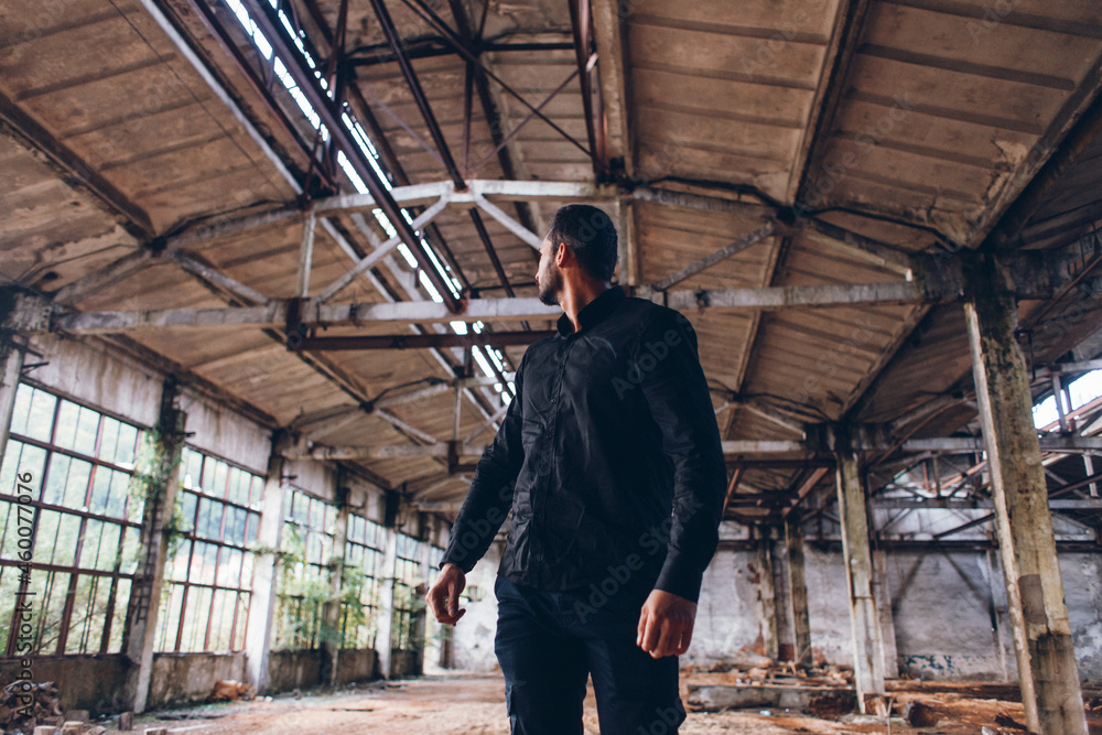 Handsome Man in Black Jacket in Dark Empty Abadoned Factory Hall 