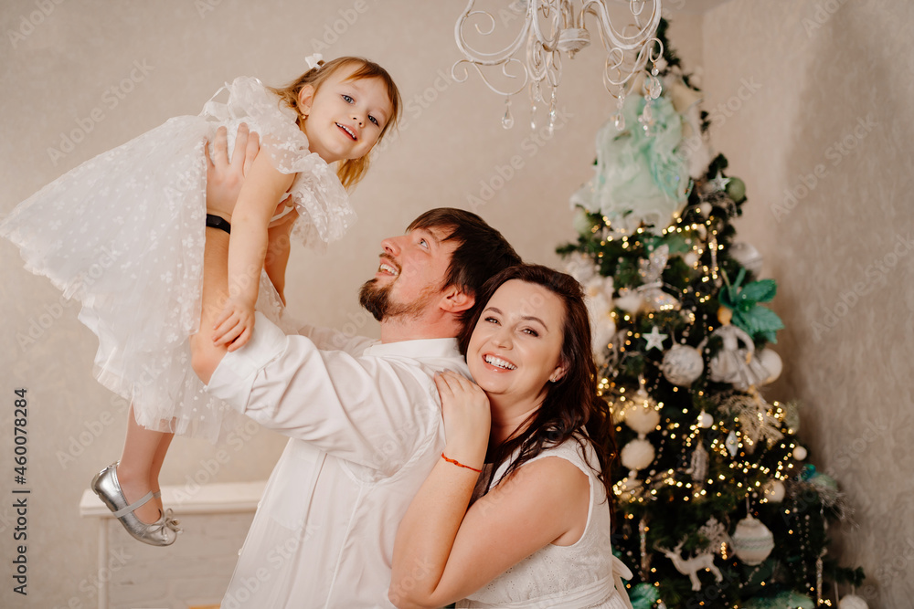 beautiful and happy family at the Christmas tree. mom, dad and daughter beautiful and happy family at the Christmas tree. mom, dad and daughter