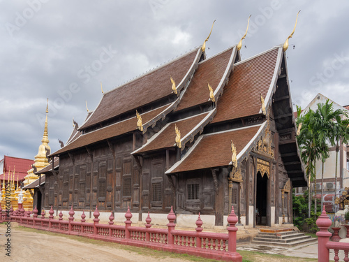 Side view of beautiful ancient wooden Wat Phan Tao buddhist temple with golden stupa, Chiang Mai, Thailand 