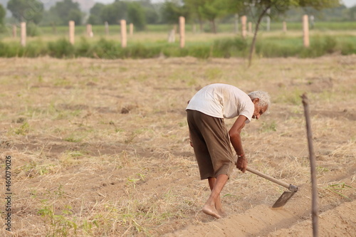 An Indian-origin farmer uses a shovel to make a raw drain of mud for water to go to the field for irrigation of crops in the field