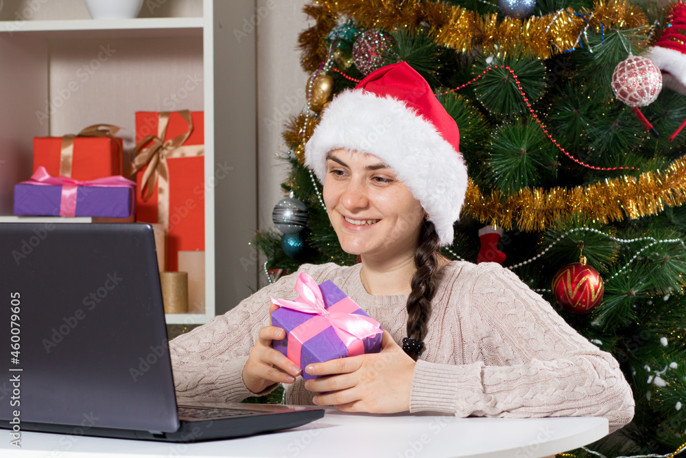 A woman in a Santa Claus hat rejoices in winter Christmas discounts in online stores