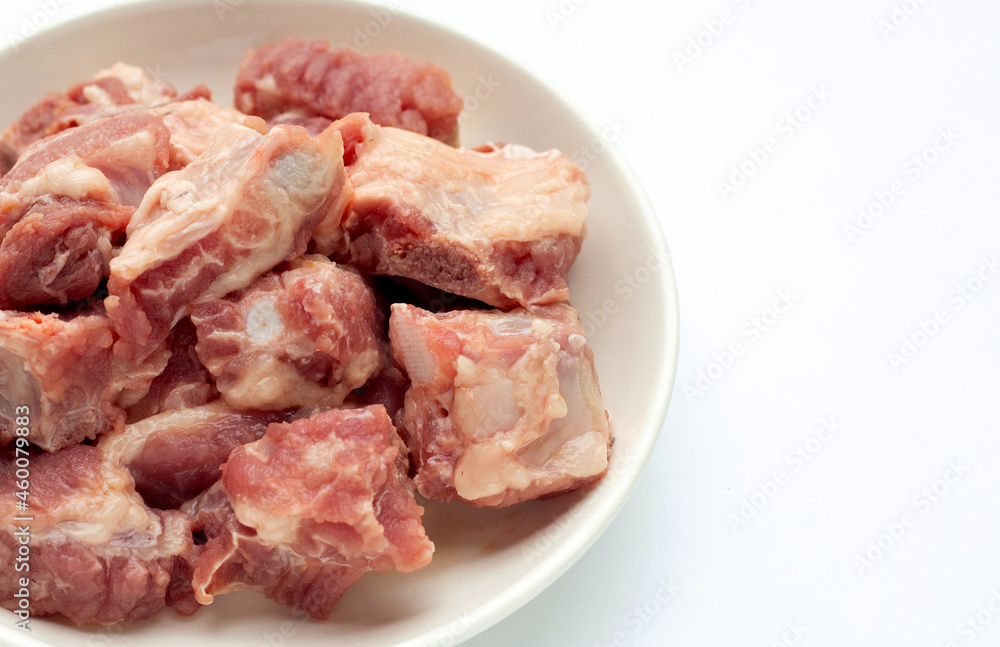 Raw pork ribs in white plate on white background.