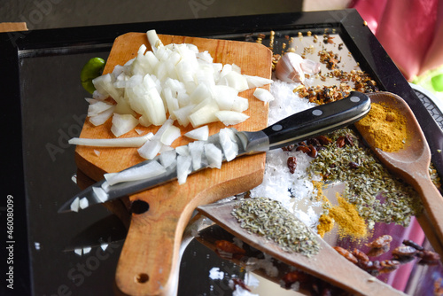 Cebolla picada con cuchillo sobre tabla de madera para cocinar comida vegana