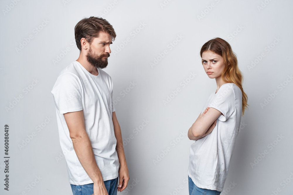 a young couple in white T-shirts with phones in their hands light background a young couple in white T-shirts with phones in their hands light background