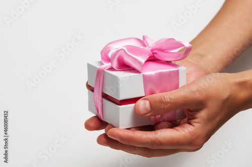 Female hands holding small gift box with ribbon on white background © Gecko Studio