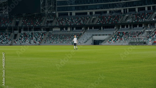 WIDE Caucasian pre teen kid boy entering the field of huge soccer stadium, holding a ball, dreaming of becoming professional player, soccer star © supamotion