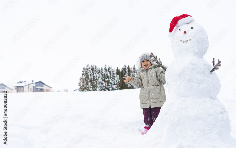child builds a snowman in the winter in the yard. concept of winter games with snow for children