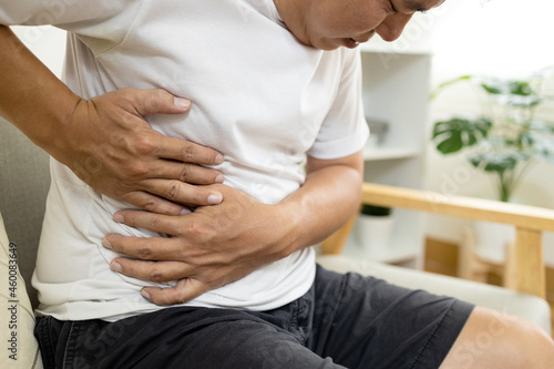 Asian male patient with abdominal pain on right side belly,painful in abdomen,irritable bowel,middle-aged man holds under the ribs,stomach ache,cirrhosis of the liver disease,liver cancer concept photo