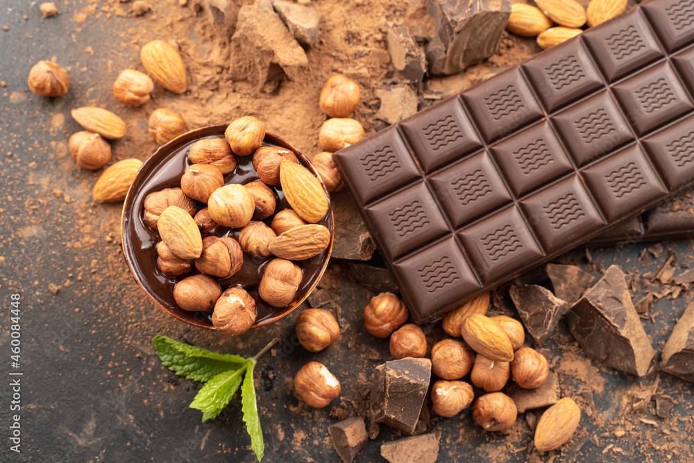 chocolate bar with hazelnuts, mint leaf, handmade sweets. Composition of bars dark chocolates hazelnuts, mint leaves on black background, top view. Pastry craft on the table for chocolate background chocolate bar with hazelnuts, mint leaf, handmade sweets. Composition of bars dark chocolates hazelnuts, mint leaves on black background, top view. Pastry craft on the table for chocolate background