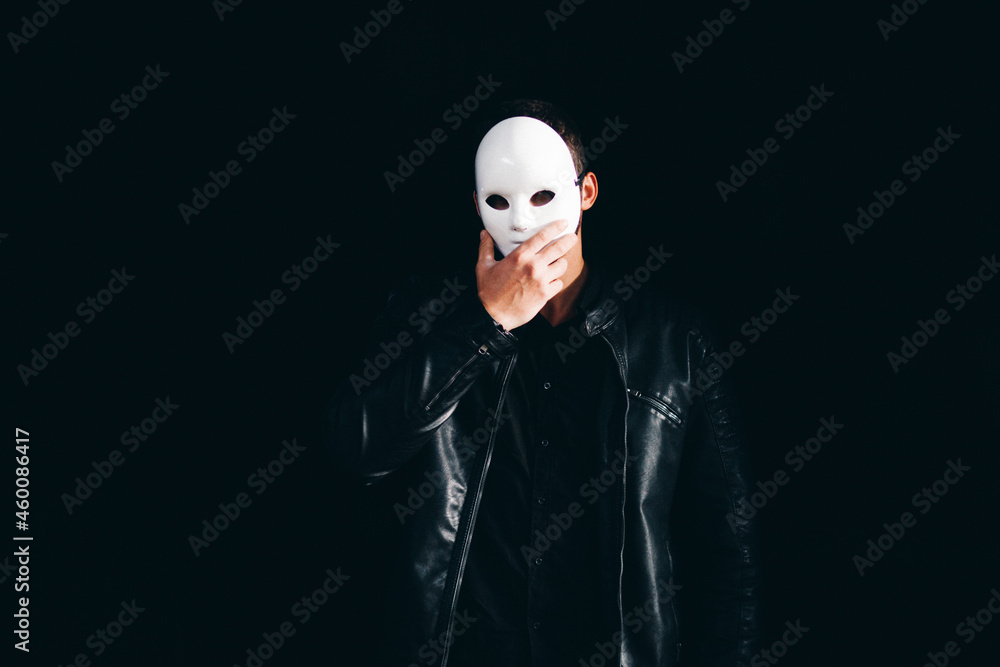 Handsome Strong Man Hides Behind a Mask in the Dark Background Handsome Strong Man Hides Behind a Mask in the Dark Background