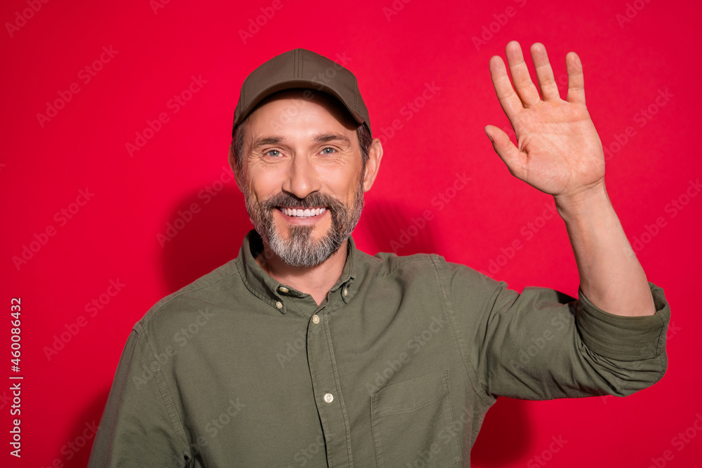 Photo portrait man wearing cap waving hand isolated vibrant red color background Photo portrait man wearing cap waving hand isolated vibrant red color background