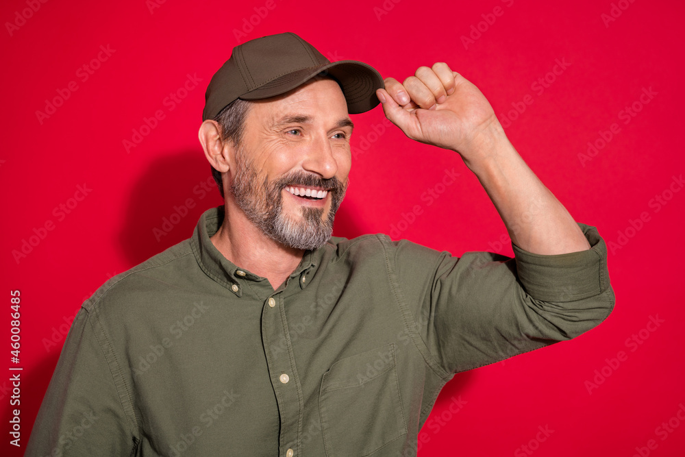 Photo of friendly age man look empty space wear khaki shirt hat isolated on red color background Photo of friendly age man look empty space wear khaki shirt hat isolated on red color background