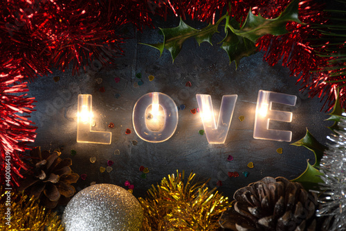 palabra amor escrita con letras luminosas, con adornos navideños alrededor photo