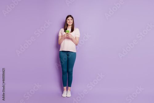 Portrait of curious interested funny blogger lady hold cellphone look empty space on violet background