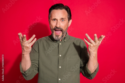 Photo of sad mature brunet man hands up wear khaki shirt isolated on red color background