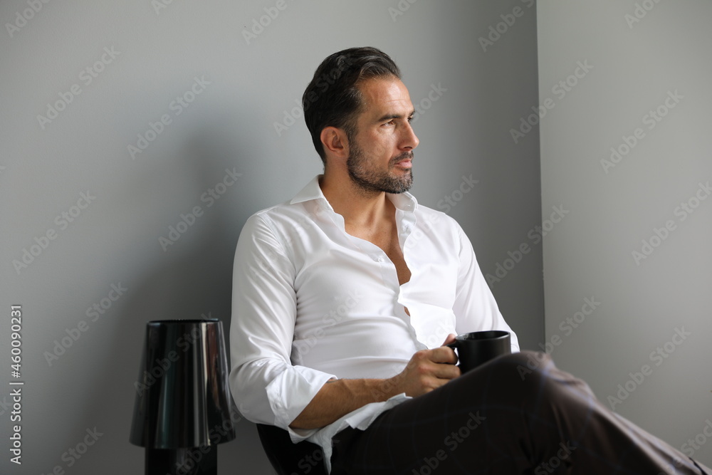 Przystojny brunet w białej koszuli podczas porannej kawy przed wyjściem do pracy. - obrazy, fototapety, plakaty 